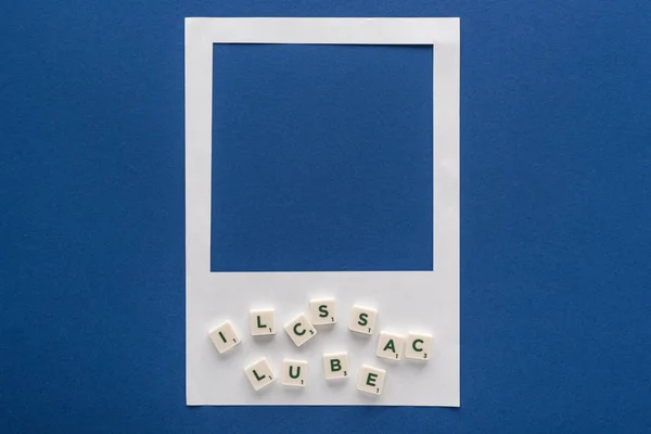 Vista superior de letras em cubos e moldura de foto branca no fundo azul — Fotografia de Stock