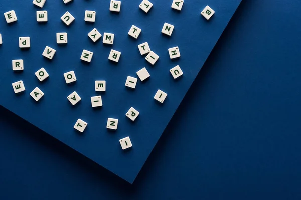 Vista superior de letras sobre cubos dispersos sobre fondo azul - foto de stock