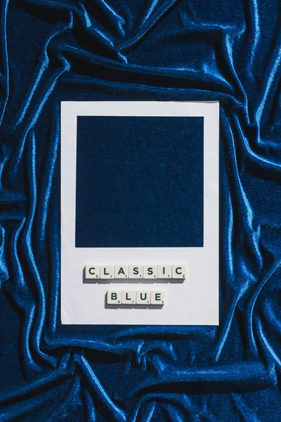 Vista superior de letras azules clásicas en cubos y marco de fotos blanco en tela de terciopelo azul - foto de stock