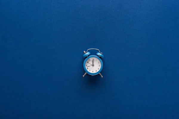 Vista superior del reloj despertador sobre fondo azul - foto de stock