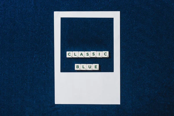 Vue de dessus du lettrage bleu classique sur cubes et cadre photo blanc sur fond bleu texturé — Photo de stock