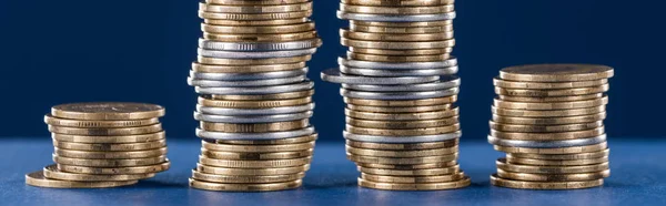 Stacks of metal silver and golden coins on blue background, panoramic shot — Stock Photo