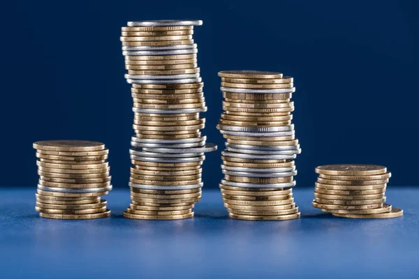 Stapel von Silber- und Goldmünzen aus Metall auf blauem Hintergrund — Stockfoto