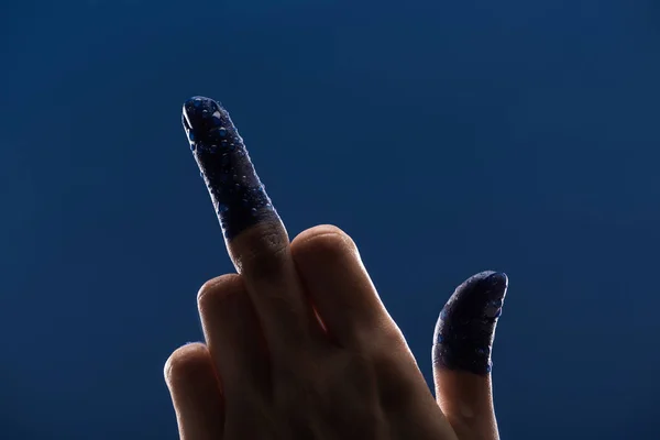 Vista recortada de la mano femenina con los dedos pintados húmedos que muestran el dedo medio aislado en azul - foto de stock