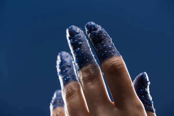 Крупный план женской руки с мокрыми окрашенными пальцами, изолированными на голубом фоне — стоковое фото