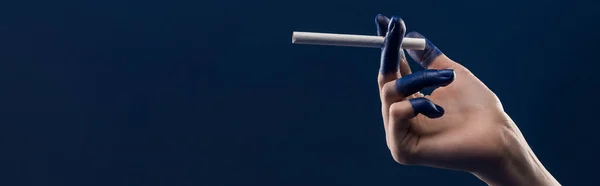 Cropped view of female hand with painted fingers holding cigarette isolated on blue, panoramic shot — Stock Photo