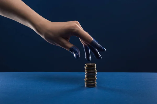 Обрізаний вид жіночої руки з розфарбованими пальцями торкаються монет ізольовані на синьому — стокове фото