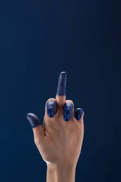 Обрізаний вид жіночої руки з розфарбованими пальцями, що показують середній палець ізольовано на синьому — стокове фото