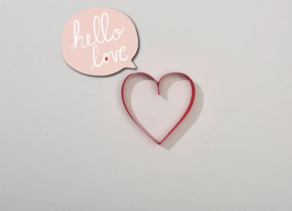 Вид зверху на червоне паперове серце на сірому фоні з привітаннями коханням у мовній бульбашці — стокове фото