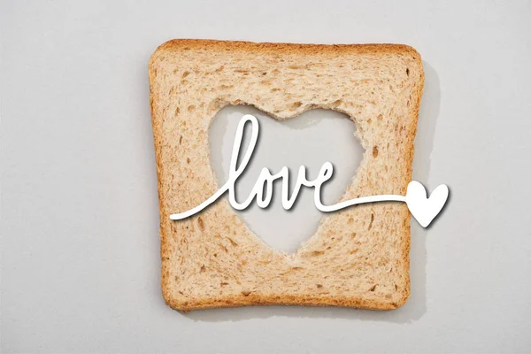 Vista dall'alto della fetta di pane con cuore intagliato e lettere d'amore su sfondo grigio — Foto stock