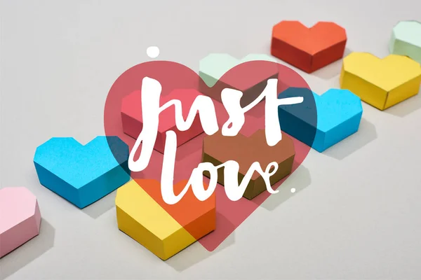 Coeurs multicolores décoratifs et juste l'amour illustration sur fond gris — Photo de stock