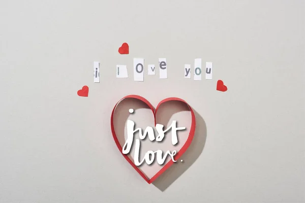 Top view of paper hearts with i love you lettering and just love illustration on grey background — Stock Photo