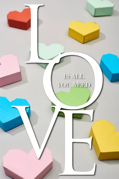 Decorative multicolored hearts on grey background with love is all you need illustration — Stock Photo