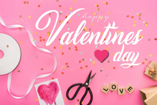 Вид зверху на валентинки конфетті, порожній компакт-диск, ножиці, подарункові коробки, вітальна листівка та любовне написання на дерев'яних кубиках на рожевому фоні з щасливою ілюстрацією дня валентинки — стокове фото