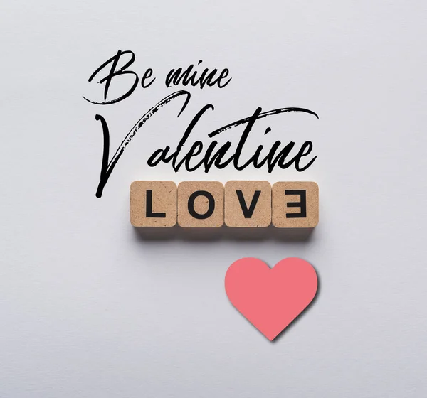 Top view of cubes with love lettering on white background with be mine valentine lettering and heart illustration — Stock Photo