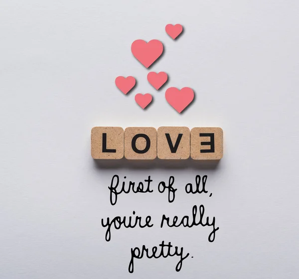 Top view of cubes with love lettering on white background with first of all you are really pretty lettering and hearts illustration — Stock Photo