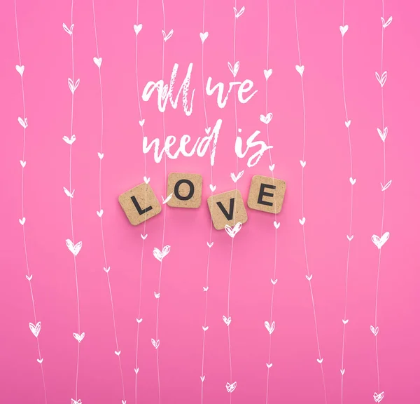 Top view of love lettering on wooden cubes on pink background with all you need is love illustration — Stock Photo