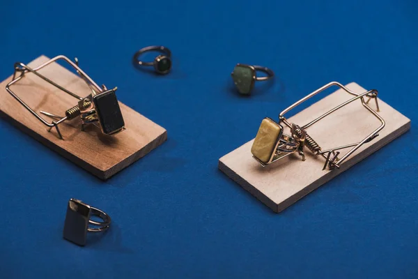Vista de perto de ratoeiras e anéis de jóias na superfície azul — Fotografia de Stock