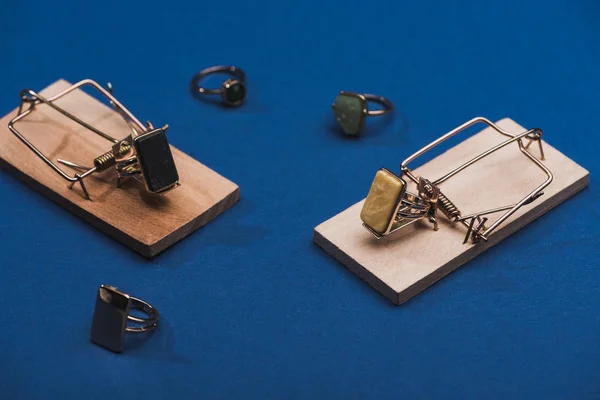 Close up view of mousetraps and jewellery rings on blue surface — Stock Photo