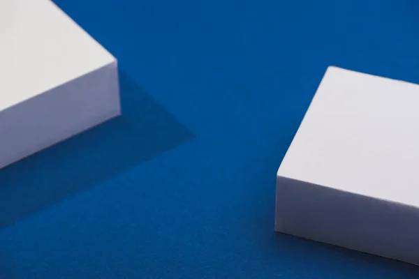 Vista de ángulo alto de cubos blancos con sombra sobre fondo azul - foto de stock