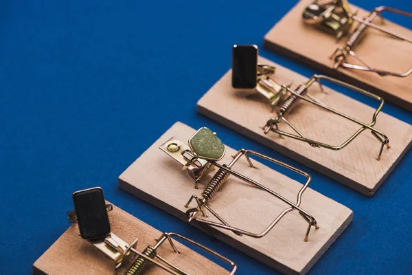 Vista de cerca de las trampas de ratón de madera con anillos de joyería sobre fondo azul con espacio de copia - foto de stock