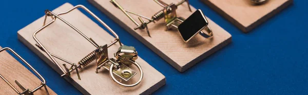 Jewellery rings in wooden mouse traps on blue surface, panoramic shot — Stock Photo