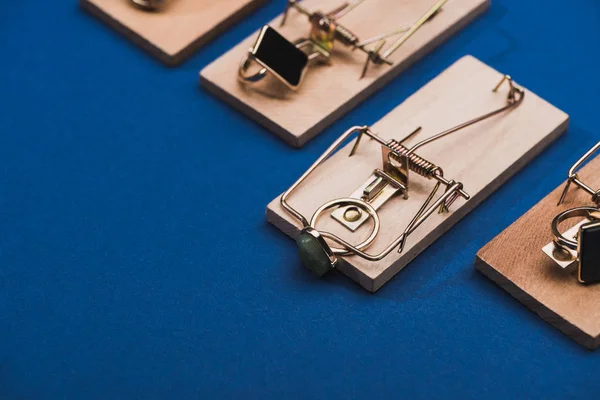 Close up view of row from mouse traps with jewellery rings on blue background — Stock Photo