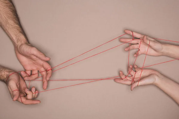 Top view of man and woman holding red string on beige background — Stock Photo