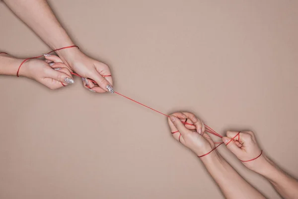 Top view of women pulling red string on beige background — Stock Photo