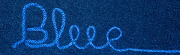 Top view of word blue from thread on blue textile, panoramic shot — Stock Photo