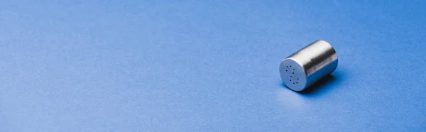 Panoramic shot of metallic salt shaker on blue background — Stock Photo