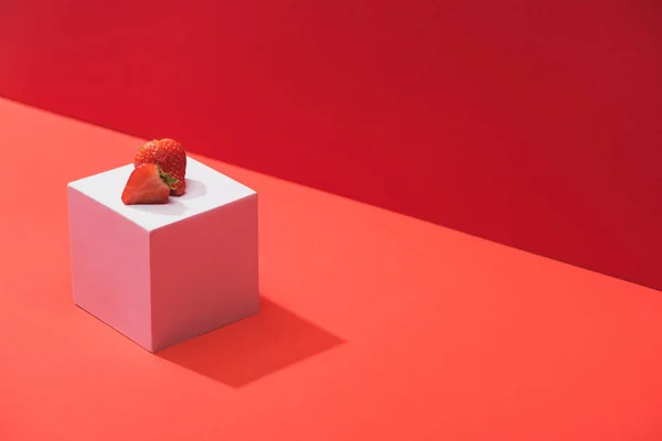 Fresh ripe strawberry on cube on red background — Stock Photo