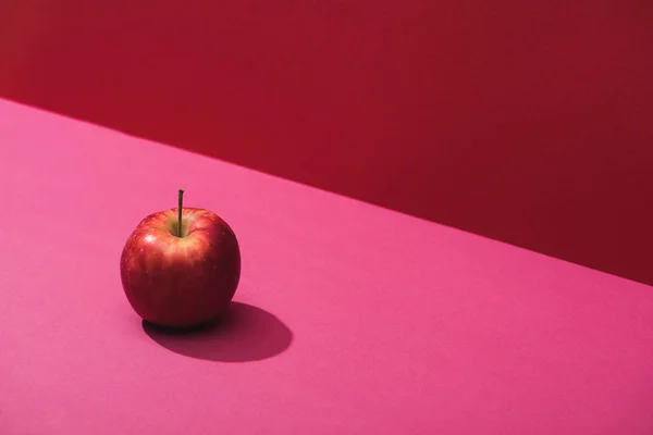 Frischer saftiger Apfel auf rotem und rosa Hintergrund — Stockfoto