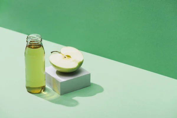 Свіжий сік біля яблучної половини та білого кубика на зеленому та бірюзовому фоні — стокове фото