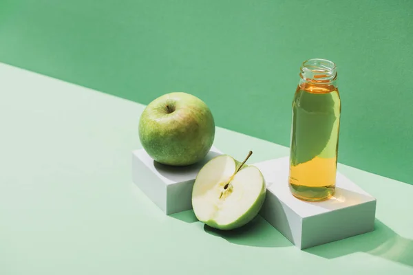 Succo fresco vicino a mele e cubetti bianchi su sfondo verde e turchese — Foto stock
