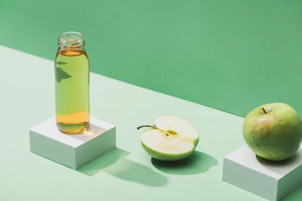 Jus frais près des pommes et des cubes blancs sur fond vert et turquoise — Photo de stock