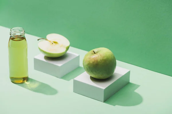 Fresh juice near apples and and white cubes on green and turquoise background — Stock Photo