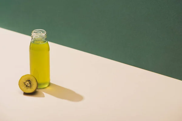 Fresh juice near kiwi on green and white background — Stock Photo