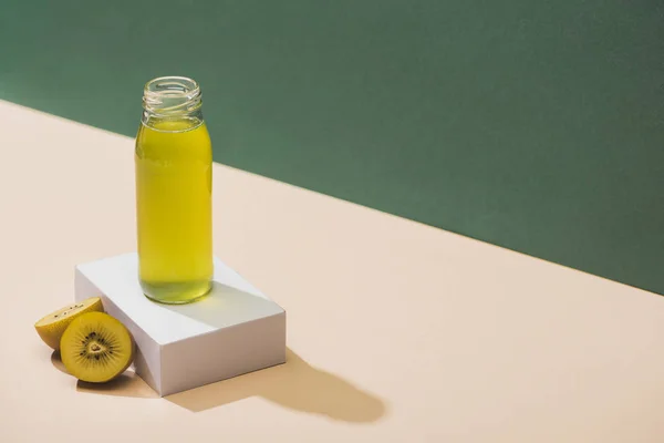 Свежий сок рядом киви и белый куб на зеленом и белом фоне — стоковое фото