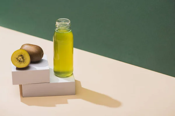 Suco fresco perto de kiwi e e cubos brancos em fundo verde e branco — Fotografia de Stock