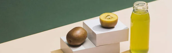 Fresh juice near kiwi and and white cubes on green and white background, panoramic shot — Stock Photo