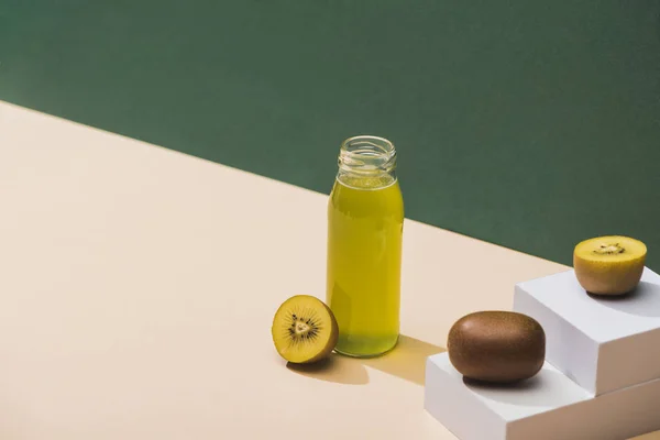 Suco fresco perto de kiwi e e cubos brancos em fundo verde e branco — Fotografia de Stock