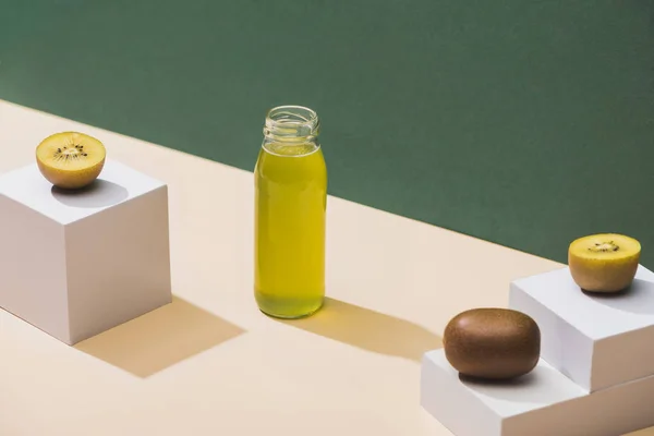 Jus frais près de kiwi et cubes blancs sur fond vert et blanc — Photo de stock