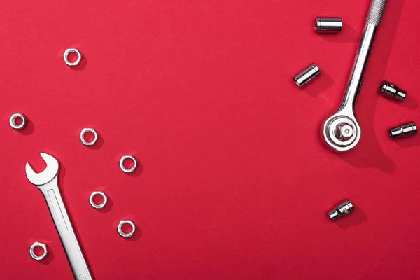 Top view of wrenches with nuts and nozzles on red background — Stock Photo