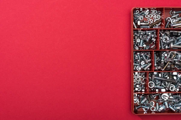 Ansicht des Werkzeugkastens mit Muttern und Holzschrauben auf rotem Hintergrund mit Kopierraum — Stockfoto