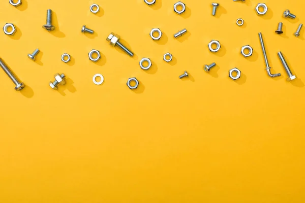 Top view of metal nuts and bolts on yellow background with copy space — Stock Photo