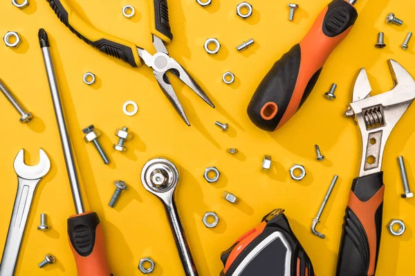 Vue du dessus de l'ensemble d'outils avec écrous et vis à bois sur fond jaune — Photo de stock