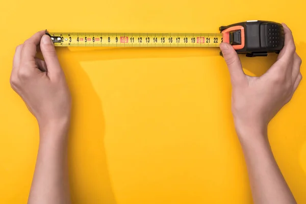 Top view of man holding industrial measuring tape on yellow background — Stock Photo
