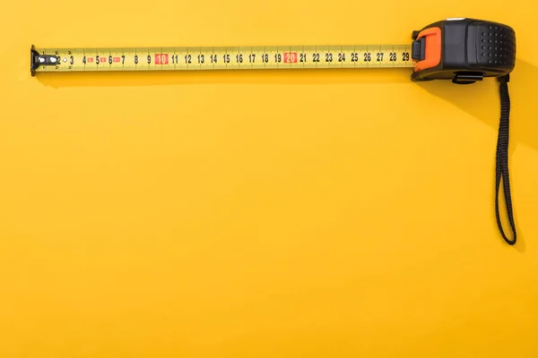 Top view of industrial measuring tape on yellow background with copy space — Stock Photo