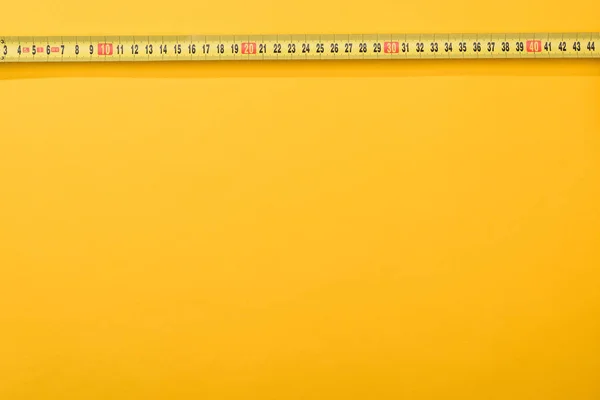 Visão superior dos números na fita métrica industrial no fundo amarelo — Fotografia de Stock